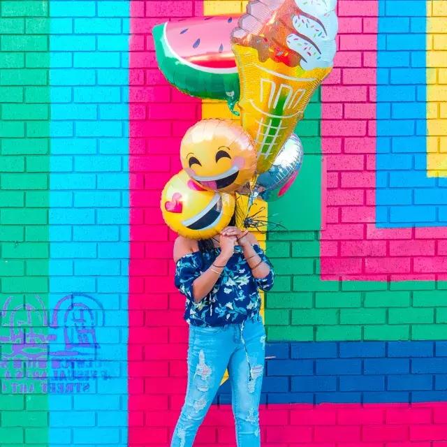 一个女孩在彩色壁画前用气球庆祝自己的生日.
